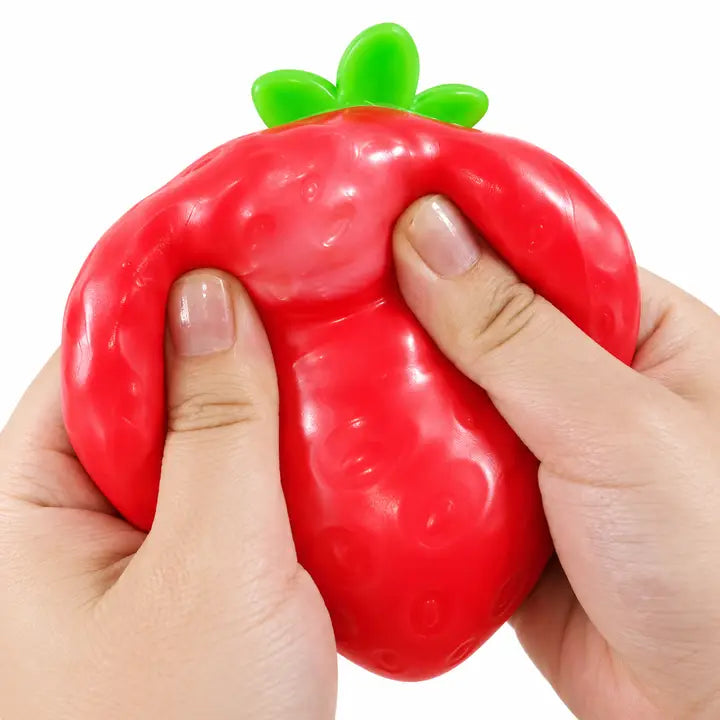 Red strawberry-shaped squishy with a green leafy top being squeezed between two hands