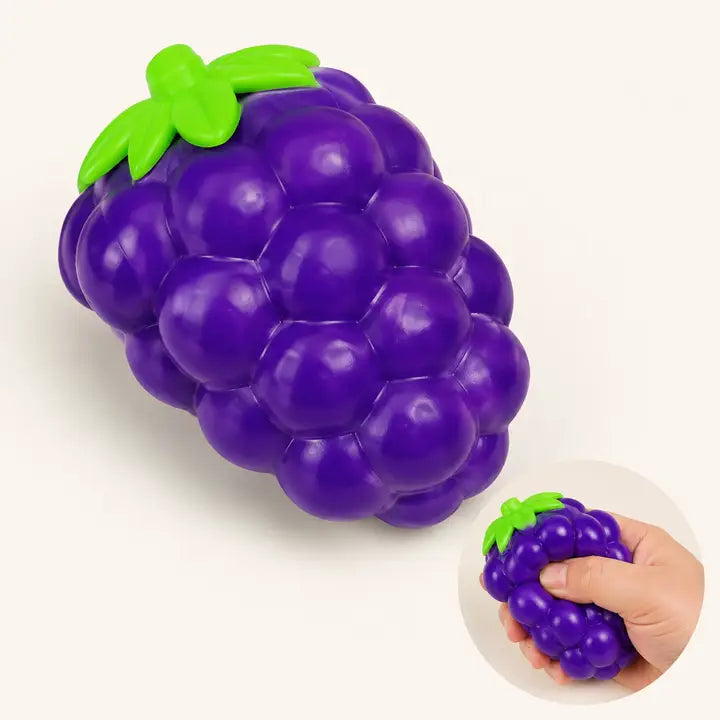 Purple grape-shaped squeeze toy with bright green leaves and stem, with inset showing hand squeezing it